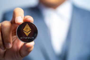 Altın Ethereum ETH 'i de içeren yumuşak odaklı bir çekim. Mavi takım elbise giyen bir iş adamında Crypto para birimi de var. Bana beyaz arkaplan ve boş alan üzerinde metin bir şey koymak için dosyaladı ve koydu ve verdi.