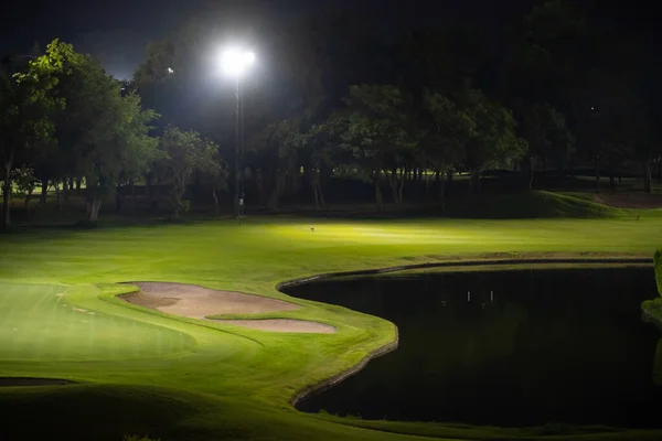 Golf sahasının güzel karanlık gece manzarası, Bunkers kumları ve yeşil çimenler, bahçe arkaplanı spot ışıklarının altında.