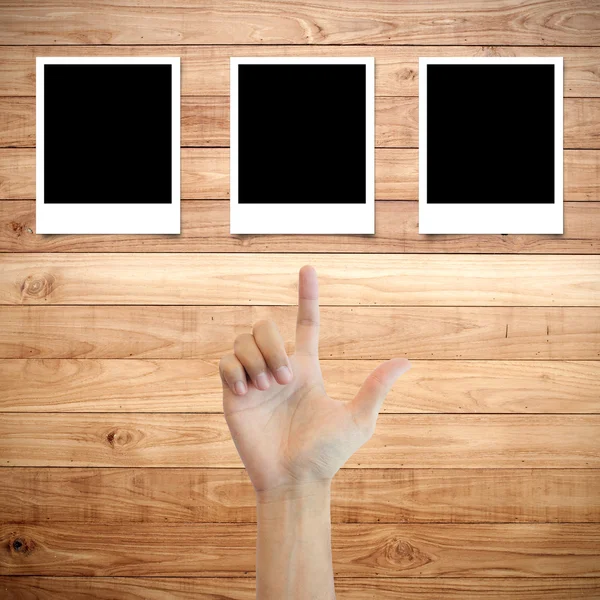 Полароидная фоторамка на деревянном фоне с указанием пальца руки — стоковое фото