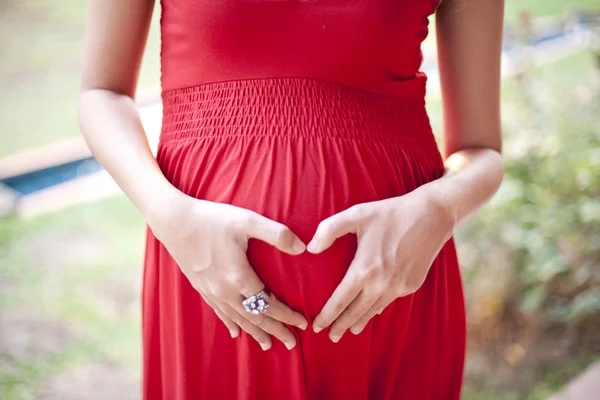 Kép a terhes nő megérintette őt kandalló, kezével — Stock Fotó