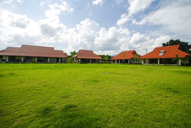 Tayland çim yeşil alan arkasında kırmızı boyalı kulübeler