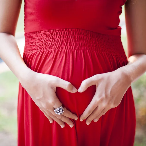 Image of pregnant woman touching her belly with depicting heart — Stock Photo, Image