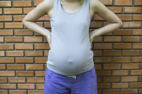 Bilden av gravid kvinna på framsidan av tegelvägg — Stockfoto