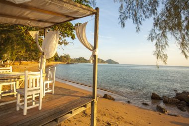 Beyaz sandalye ve masa üzerinde denize güzel manzaralı bir balkon