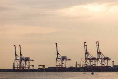 Konteyner yığınları ve vinç kargo mallar için gün batımında Tersanesi