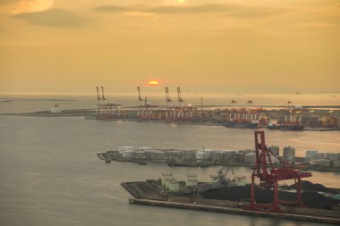 Konteyner yığınları ve vinç kargo mallar için gün batımında Tersanesi