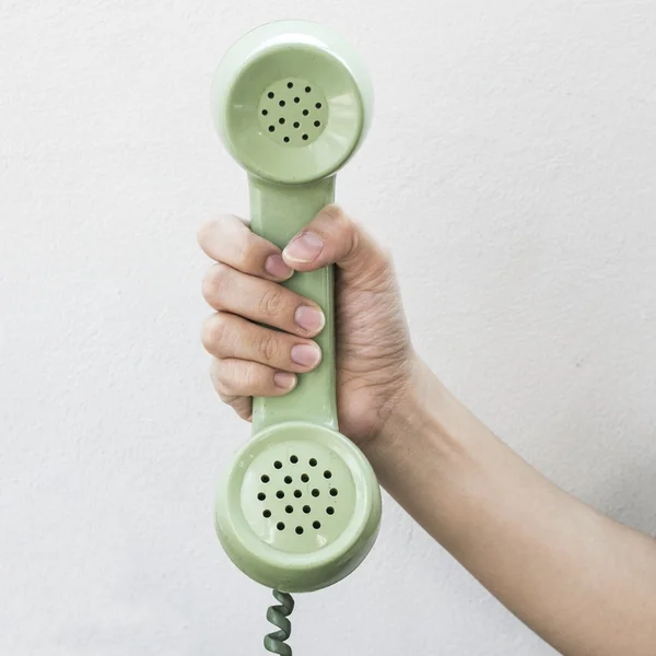 Tenuta a mano vintage telefono colore verde su sfondo bianco parete — Foto Stock