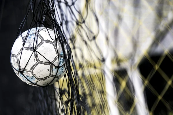 Un pallone da calcio bloccato sulla rete dietro porta — Foto Stock