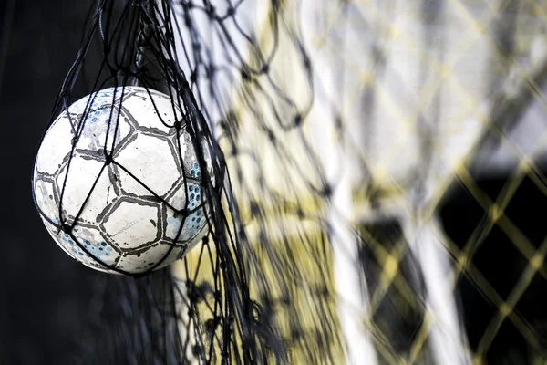 Un ballon de foot coincé sur le filet derrière le but — Photo