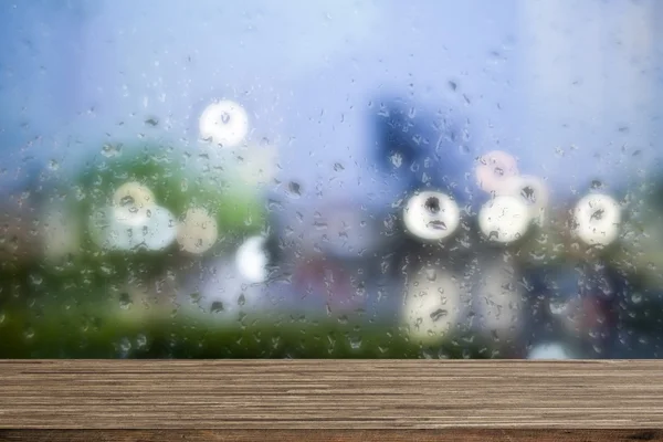 Wooden desk with water drops windows background — Stock Photo, Image