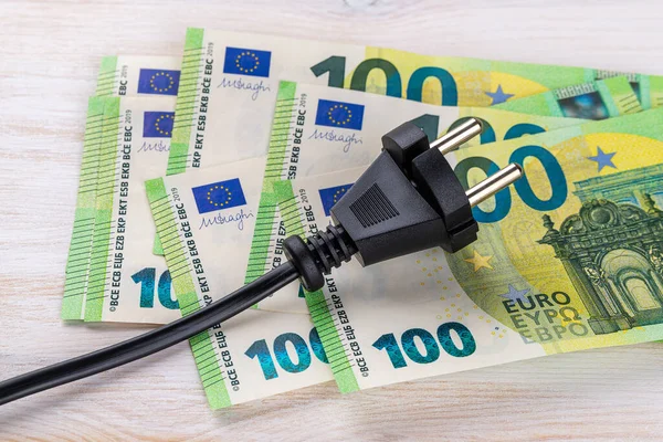 100 Euro 'luk banknotlarda siyah elektrik prizi. İkametgah müşterileri ve iş kullanıcıları için elektrik maliyetinin artırılması. Elektrik faturaları. Elektrik fiyatları kavramında artış. Üst görünüm. 
