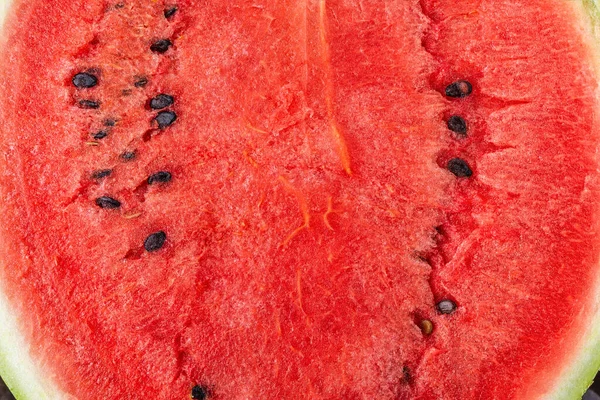 Ripe juicy watermelon with dark seeds macro texture. Freshly cut red sweet watermelon close-up. Slice of delicious organic water melon pulp. Fresh summer fruit abstract background. Full frame.