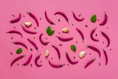 Çiğ kırmızı biber, taze yeşil fesleğen yaprağı, biraz sarımsak karanfili ve leylak arkaplanının üzerine karabiber taneleri. Gıda tasarımı için baharat yaratıcı kompozisyon. Düz yatıyordu. Üst görünüm.