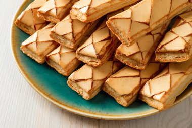 Bir yığın İtalyan çıtır fırını Sfogliatine cam bisküvileri ahşap masanın üzerinde turkuaz bir tabakta. Tatlı kahvaltı için kayısı kadehli lezzetli puf böreklerinden yakın çekim. Üst görünüm.