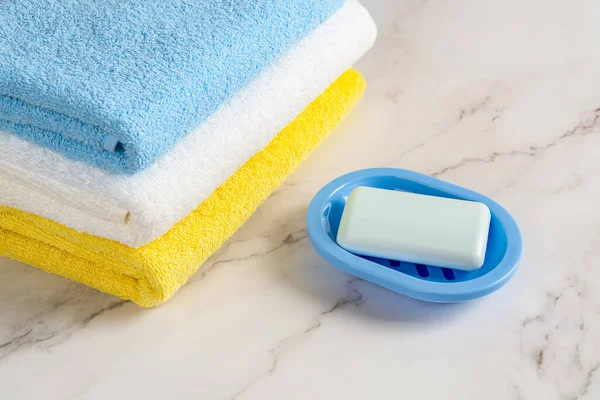 新的矩形肥皂条蓝色盘子靠近一堆彩色棉纱毛巾在大理石表面 用肥皂洗手 去洗澡吧卫生 纯洁和卫生用品的概念 后续行动 — 图库照片