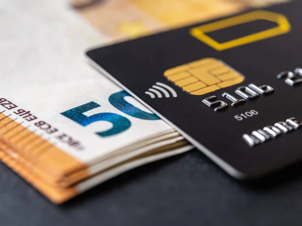 50ユーロ紙幣マクロ上のクレジットカード 現金引き出しや商品やサービスの支払いのためのブラックデビットカード チップと非接触決済技術を持つ銀行のチャージカード Dof — ストック写真