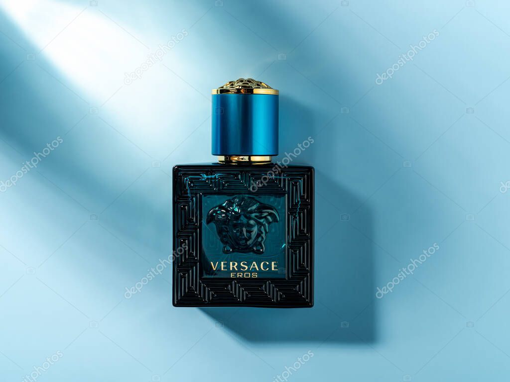 Varna, Bulgaria, January 03, 2022. Versace Eros perfume in a rectangular glass bottle on a bluee background. Stylish men perfume produced by Gianni Versace luxury fashion company. Top view.
