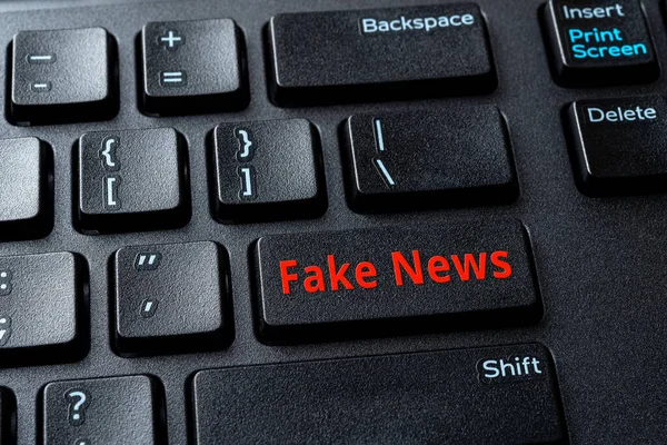 Fake News enter key on the black pc keyboard. Spread false information in the media concept. Propaganda, manipulation and hoax on the Internet. Computer enter key with warning message. Top view.