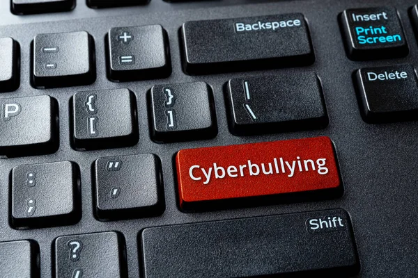 Cyberbullying word on a computer keyboard button. Laptop enter key with message cyberbullying. Concept of bullying, abusive or threatening writing or speech on the internet. Antisocial media. Top view.