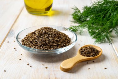 Cam tabakta çiğ dereotu tohumları ve taze yeşil dereotunun yanında tahta kaşık. Doğal baharatlar ve baharatlarla yemek pişirmek. Anethum bitkisel ilaçlar için meyve topluyor. Ön görünüm.