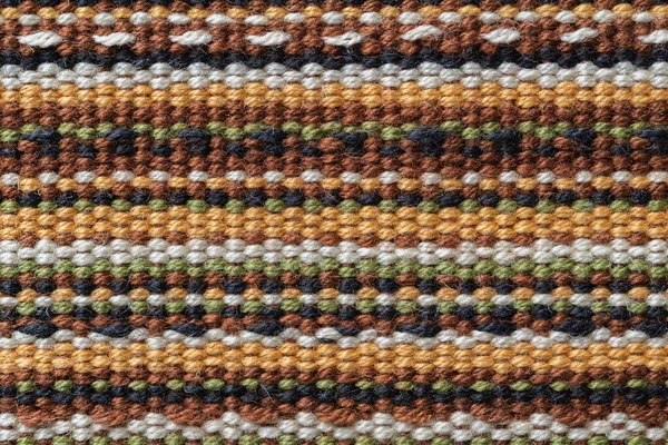 Plain weave fabric macro texture. Cloth background with horizontal strips of white, yellow, green, brown and black colors. Textile surface. Colorful woven fabric as design element. Weft and warp. Closeup.