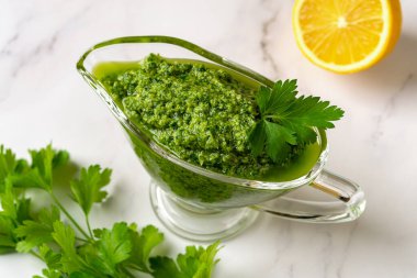 Masadaki et suyuna soslu sosa batırma sosu. Taze maydanozdan yeşil sos, sarımsak karanfili, zeytinyağı ve limon suyu. Taze bitki ve baharatlı salsa verde. Sağlıklı çeşni. Üst görünüm.