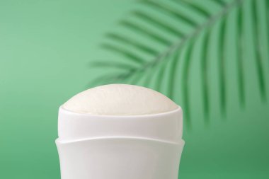 Yeşil arka plana karşı katı terleme önleyici makro. Beyaz plastik bir tüpte vücut deodorantı. Hijyen, vücut bakımı ve tuvalet malzemeleri konsepti. Terlemeyi azaltmak için makyaj malzemeleri. Ön görünüm.