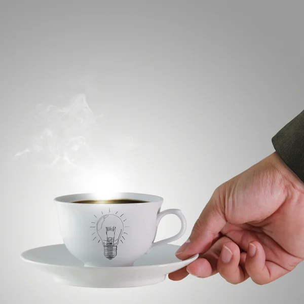 Hand and a cup of coffee with light bulb drawing as concept — Stock Photo, Image