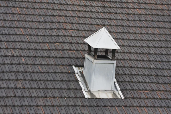 Metalen schoorsteen op zwart betegeld dak — Stockfoto