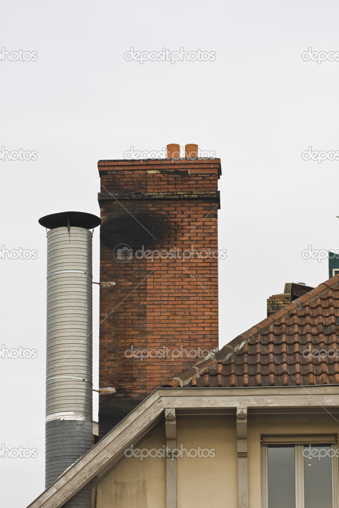 red brick chimney and metal chimney on tiled roof