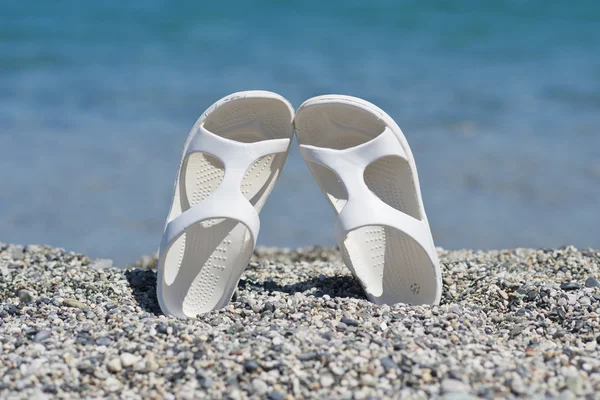 Witte sandalen op het strand — Stockfoto
