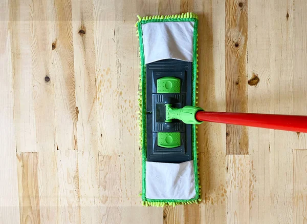 Cleaning wooden floor with mop, laminate floor top view.