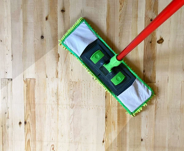 Cleaning wooden floor with mop, laminate floor top view.