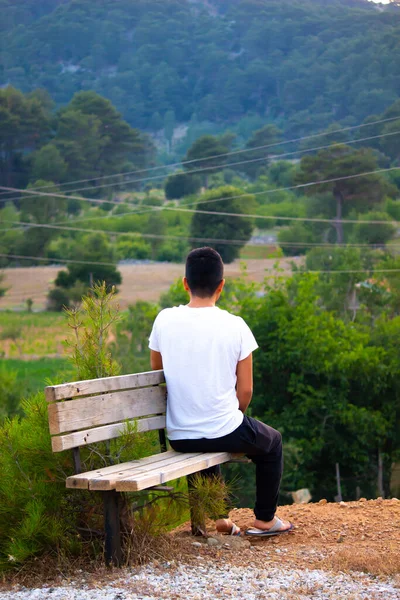 lonely man sitting on bench watching nature view. contemplation and rest concept. 