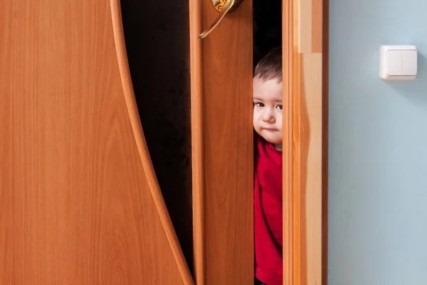Criança espreitando por trás da porta — Fotografia de Stock