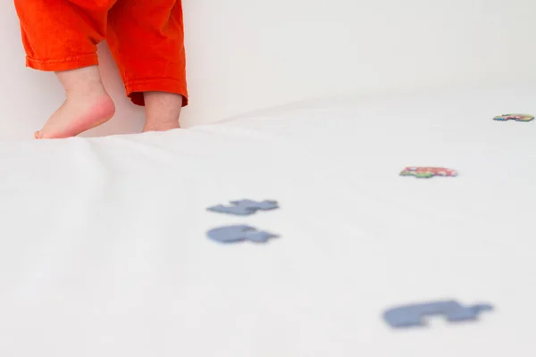 Les jambes de l'enfant, qui se tient sur le lit — Photo