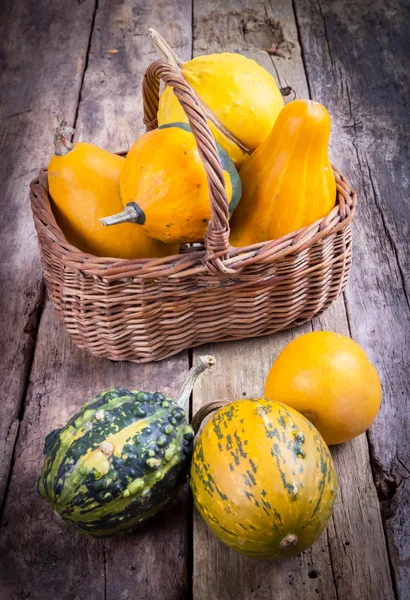 Pompoenen op een houten tafel en mand — Stockfoto