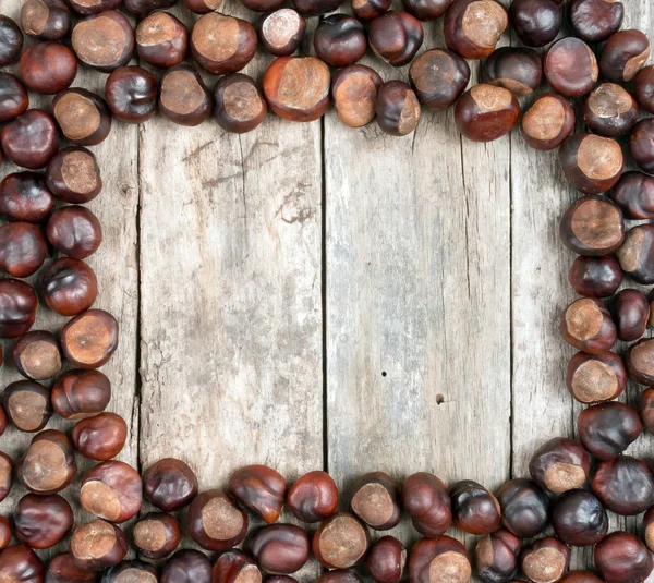 Frame with chestnuts on wooden desk — Stock Photo, Image