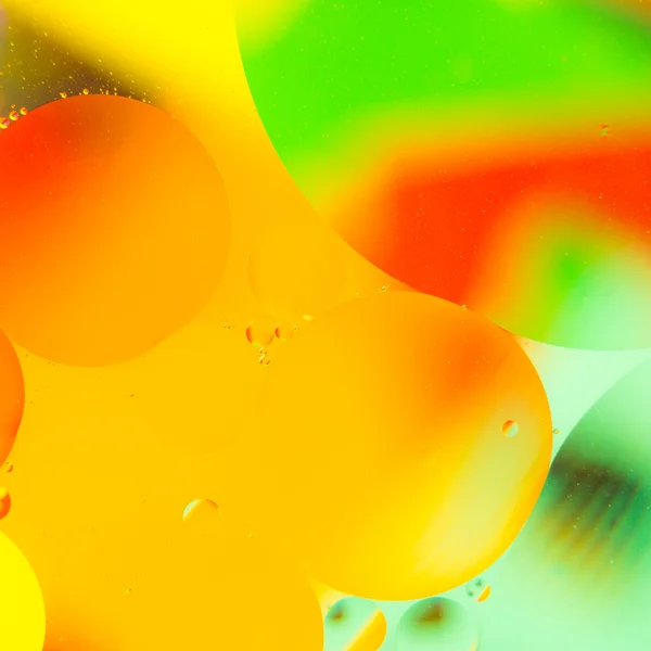Oil drops in water on a coloured background — Stock Photo, Image
