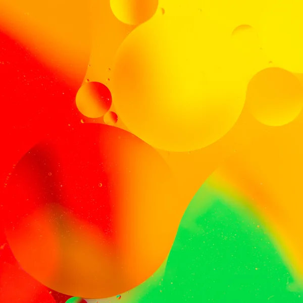 Капли масла в воде на цветном фоне — стоковое фото
