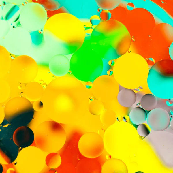 Gotas de óleo na água sobre um fundo colorido — Fotografia de Stock