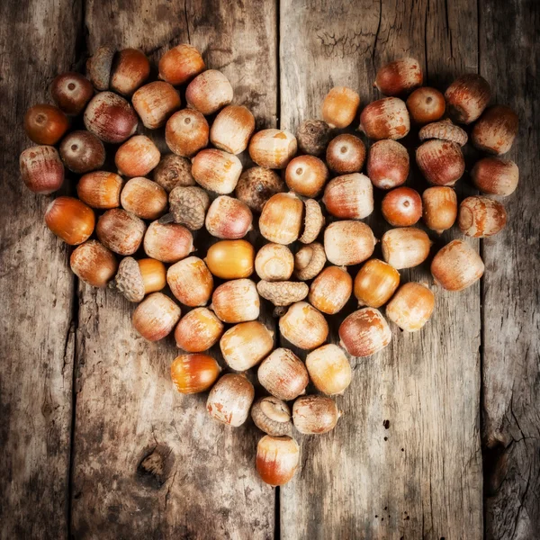 Ghiande che formano un cuore su uno sfondo di legno — Foto Stock