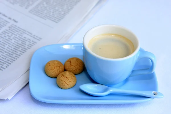 Light blue Espresso cup, Italian almond cookies and newspaper — Stock Photo, Image