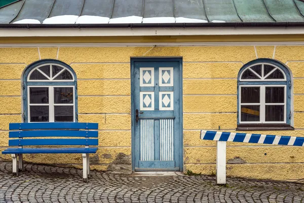 Желтый дом с синей скамейкой — стоковое фото