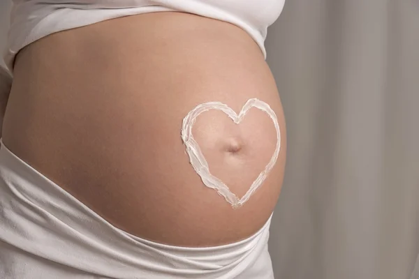 Cream heart on baby bump — Stock Photo, Image