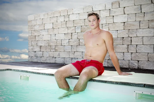 Hombre guapo sentado en la piscina — Foto de Stock