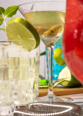 Çeşitli kokteyllerle kokteyl partisi. Zeytinli bir martini bardağını kapat.
