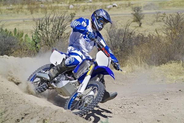 Driver goes downhill leaving a trail of dust with his motocross bike — Stock Photo, Image