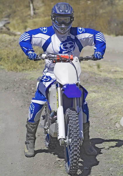 Föraren går sluttande lämnar ett spår av damm med sin motocross cykel — Stockfoto