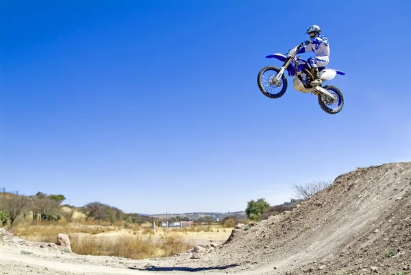 Uma foto de um motociclista fazendo uma acrobacia e salta no ar — Fotografia de Stock